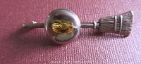 Close-up front view of vintage sterling silver curling broom brooch with yellow glass bead showing design details