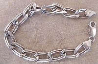 Silver link bracelet with elongated oval links and lobster claw clasp marked 925 shown on flat surface.
