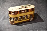 Front right angle view of metal double decker streetcar collectible ornament showing the white roof with pantograph and yellow/brown sides with L.C.C. marking.