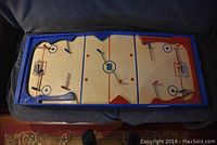 Top view showing the painted hockey rink, player rods, and goals inside a blue wooden frame.