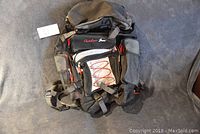 Full view of the black Outdoor Gear backpack lying flat showing front pockets and straps.