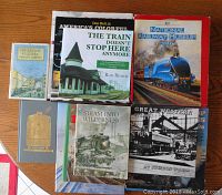 Overview of 9 train-related books spread on a wooden surface showing varied covers and conditions. Focus on titles about railway museums, locomotive history, and train photographs.