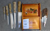 Photo of 10 knives with wooden handles and a hand-painted wooden knife holder featuring floral folk art decoration.