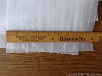 Close-up photo showing width and thickness of foam packing material next to a wooden ruler