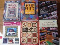 Photo of six quilting books with colorful quilt block patterns on covers, including titles like Quick Quilts from the Heart and Scrap Quilts
