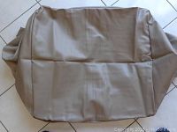 Beige synthetic protective cover laid out on floor, showing smooth fabric surface and box shape.