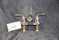 Front angle view of the nickel finish bathroom faucet showing the dual handles and central spout with the attached mounting hardware.