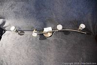 Front view of brushed nickel curved ceiling light fixture with 4 LED bulb holders on a dark fabric background.