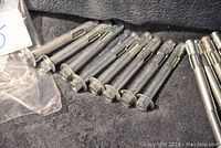 View showing 17 metal heavy lag bolts laid out in two groups based on length on a textured dark surface