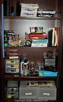 Full view of three wooden shelves displaying multiple office supplies including paper, folders, manila envelopes, office tools, and storage drawers.