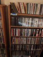 Front view of wooden CD shelf with various CDs on shelves