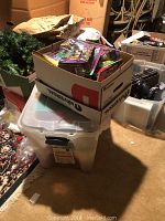 Stored plastic bin with several unopened Teenage Mutant Ninja Turtle toys and other packaged items.