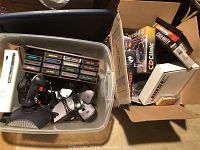Photo of Atari game cartridges, joystick controller, and Xbox 360 console visible in plastic bin.