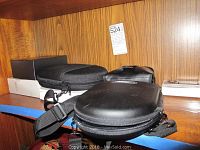 Three black zip cases and one white box on wooden shelf
