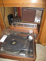 Photo showing the full set of audio equipment inside wooden cabinetry including turntable, equalizer, receiver, cassette deck, and speaker