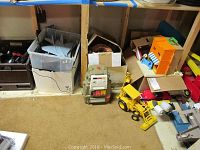 Wide view of the lot showing the toy boxes, 2-XL robot, backhoe loader, toy cars, and Playskool structure.