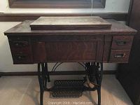 Closed antique wooden sewing machine cabinet, showing top surface and drawers