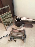 Photo of washboard, crock, wooden tray, and vintage clothes dryer wringer on floor