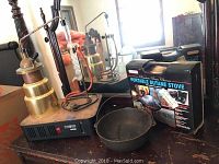 Lot overview showing distiller, cast iron pot, and boxed butane stove