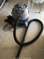 Full view of shop vac with hose attached showing overall unit size and condition.