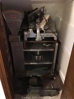 Toledo industrial scale and metal meat slicer all inside a small closet space, showing the general contents of the lot.