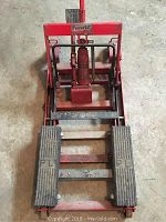 Top view of red hydraulic lift showing rubber foot pedals and hydraulic jack
