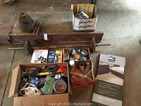 Barbell, weight plates, and assorted hardware boxes on garage floor