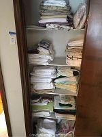 View of full linen closet with multiple shelves stacked with folded sheets, blankets, and towels.