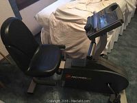 Side profile of ProForm 975S recumbent exercise bike showing padded seat and backrest, pedals and console mount.