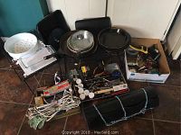 Overall photo of kitchen lot showing Pyrex dish, skillets, pots, kitchen mat, and a box with kitchen tools and accessories