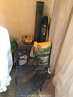 Full view of garden supplies including bag of Scotts Turf Builder Weed & Feed, black metal tiered plant stand, rolled garden fencing, seed packets, and miscellaneous items.