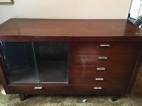 Full front view showing buffet with glass sliding doors on left side, four drawers on right side, medium dark wood finish with some surface wear and stains