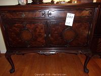 Full front view showing drawer, doors, carved apron and legs