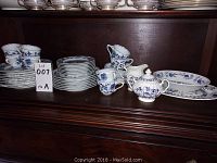 Full set of Blue Danube dinnerware service for 8 with Blue Nordic serving pieces displayed on a wooden shelf.