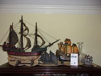 Wide shot of entire lot on a surface showing 4 decorative ship models and 1 glass ship decanter.