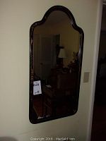 Full view of the black lacquer wall mirror with Asian style painted designs, mounted on wall.