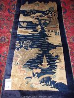 Full view of runner on red patterned floor showing navy border and central landscape motif