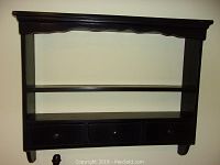 Full front view of the black wooden wall shelf showing three drawers and a plate groove at the top shelf.