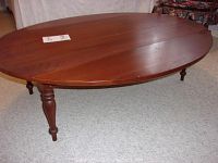 View of oval top with drop leaves raised, showing smooth wood surface and sturdy legs.