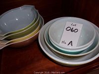 Stacked oval Pyrex bowls in pastel colors with pouring spouts, showing varied sizes and colors including white, green, yellow, and brown.