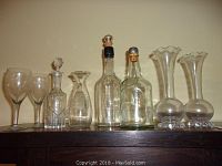 Full set of 8 glassware pieces including glasses, vases and bottles displayed on wooden surface