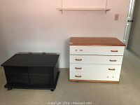 Black TV stand and white laminate dresser side by side against a wall.