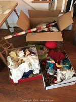 Top-down photo showing three boxes with holiday decorations including rolled-up flag/banner, ornaments, and a red stocking.