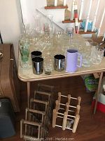 Wide view of table top filled with assorted glassware and wine racks beside it