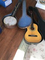 5-string banjo with brown crocodile pattern resonator and case alongside Castilla classical acoustic guitar in case