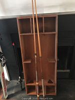 Large wooden vintage Skittles game frame with two wooden cue sticks placed inside it, showing compartments and triangular slots for pieces.