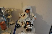 Three Eskimo-style dolls on a table with other objects around.