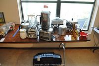 View showing entire table with Vita Mix blender and assortment of kitchenware including bakeware and dishes.