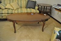 Wooden coffee table in a room setting, showing the profile and side view, legs and finish condition visible.