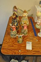 Six Jim Shore angel figurines arranged on a wooden table, showing variety of sizes and dress designs.